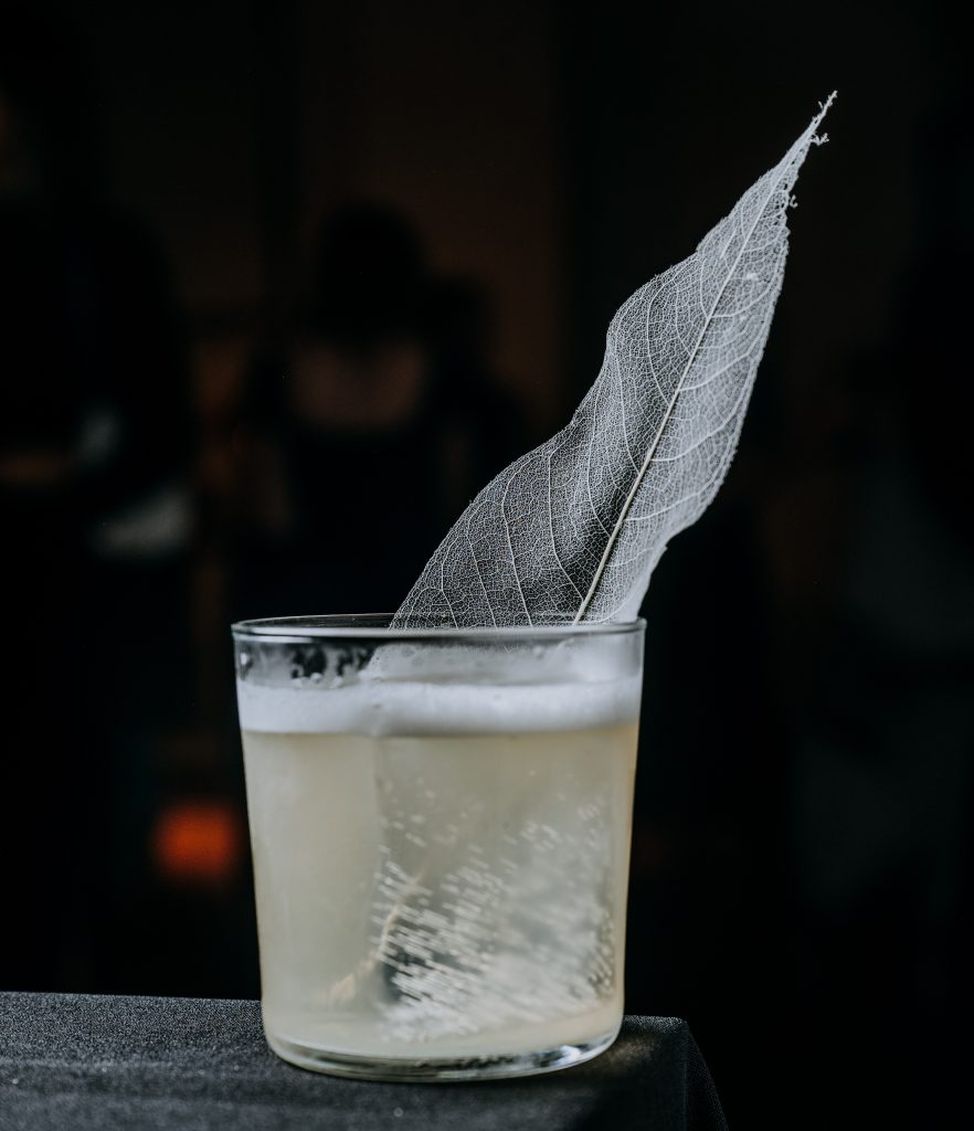 Coctel con hoja decorativa para coctelería para eventos con fondo negro