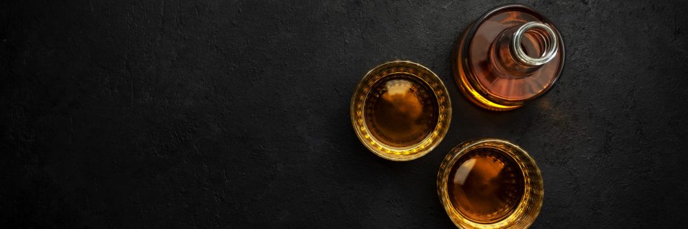 American bourbon whiskey in glasses and bottle, black background with negative space
